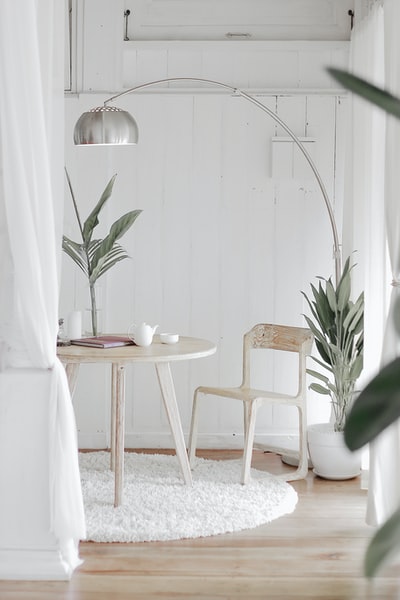 在白色地毯上的圆桌前面放着白色的钢椅